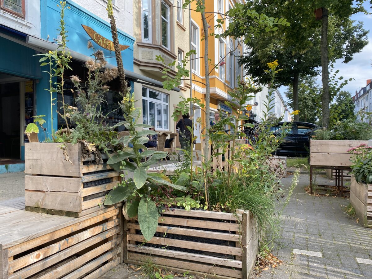 Grün bepflanzte Holz-Hochbeete und Holzbänke auf einem Parkplatz in der Vegesackerstr. Das erste dauerhafte Parklet in Bremen-Walle.